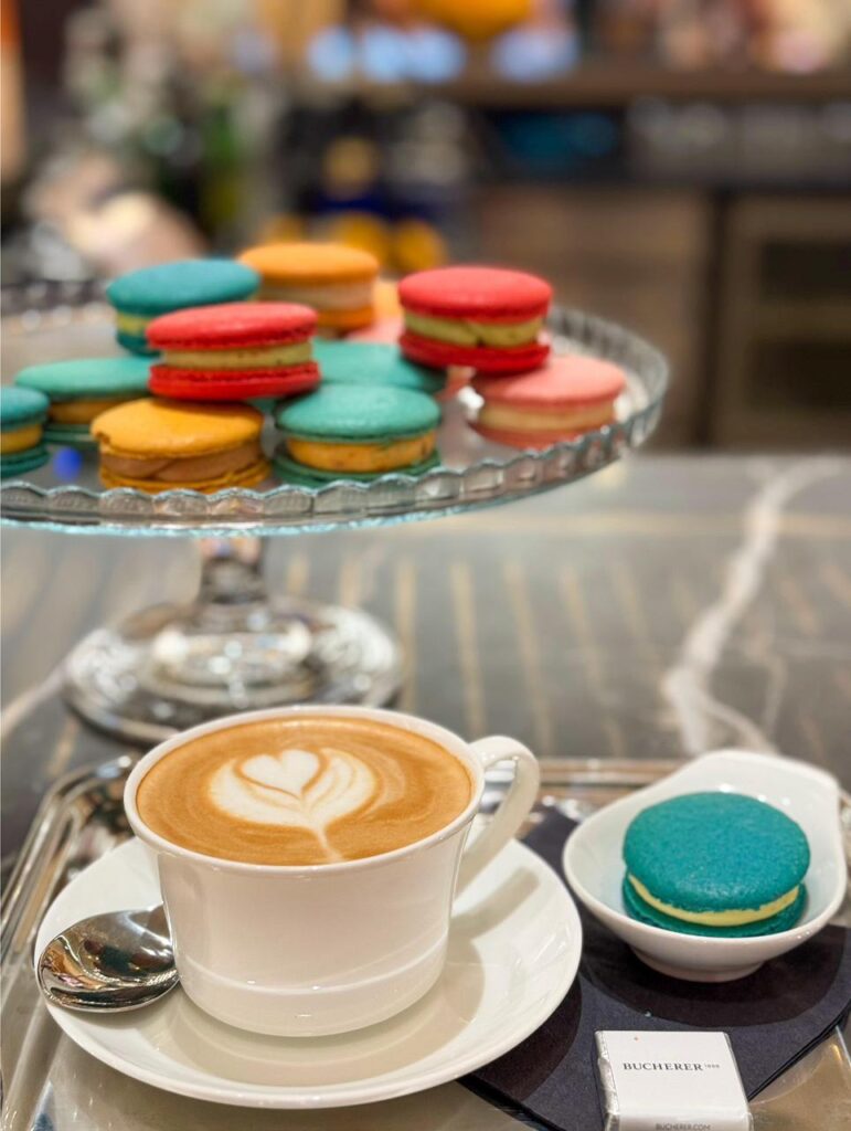 Kaffee und bunte Macarons auf einem Tisch.